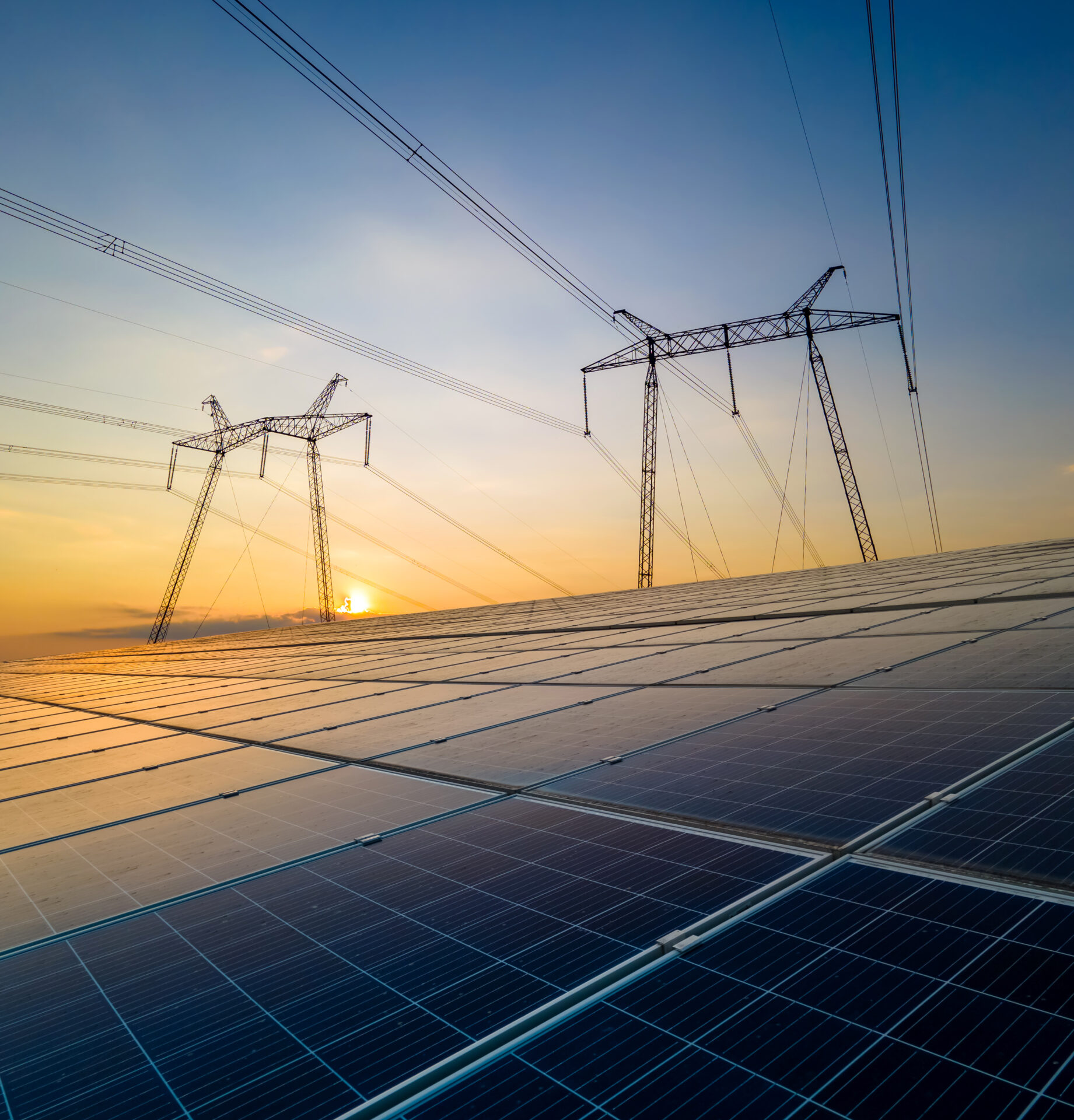 High voltage pylons with electric power lines transfering electricity from solar photovoltaic sells at sunrise. Production of sustainable energy concept.